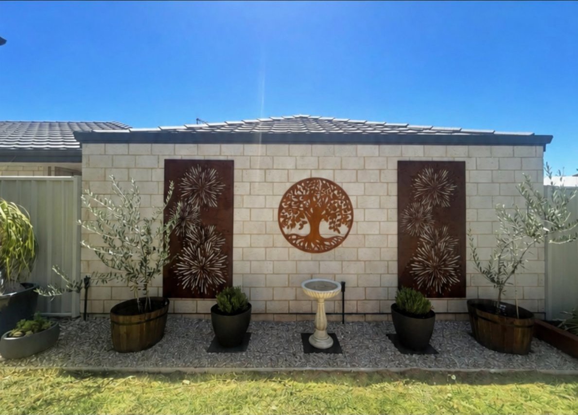 Finished backyard with paving, potted plants and garden wall art